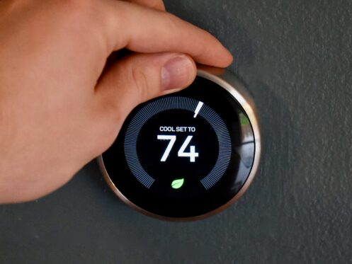 Hand adjusting temperature on smart thermostat