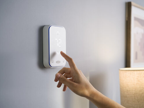 A woman checking the smart thermostat in her Billings home.
