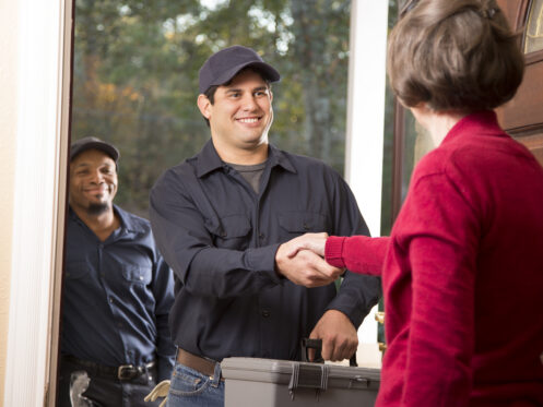 HVAC technicians shaking hands with homeowner